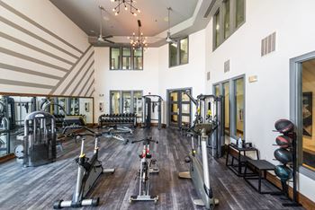 a gym with weights and cardio equipment in a building with high ceilings